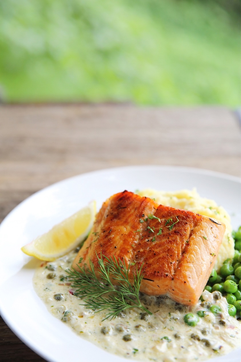 Pan-seared salmon over lemon-dill caper sauce with peas and mash
